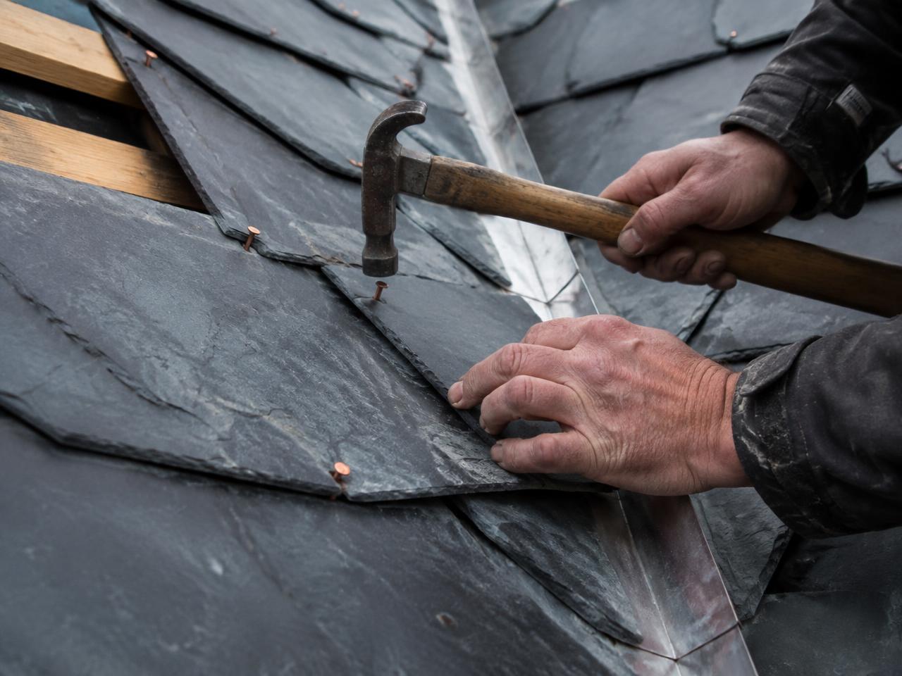 Slates being fixed with copper nails beside a lead valley