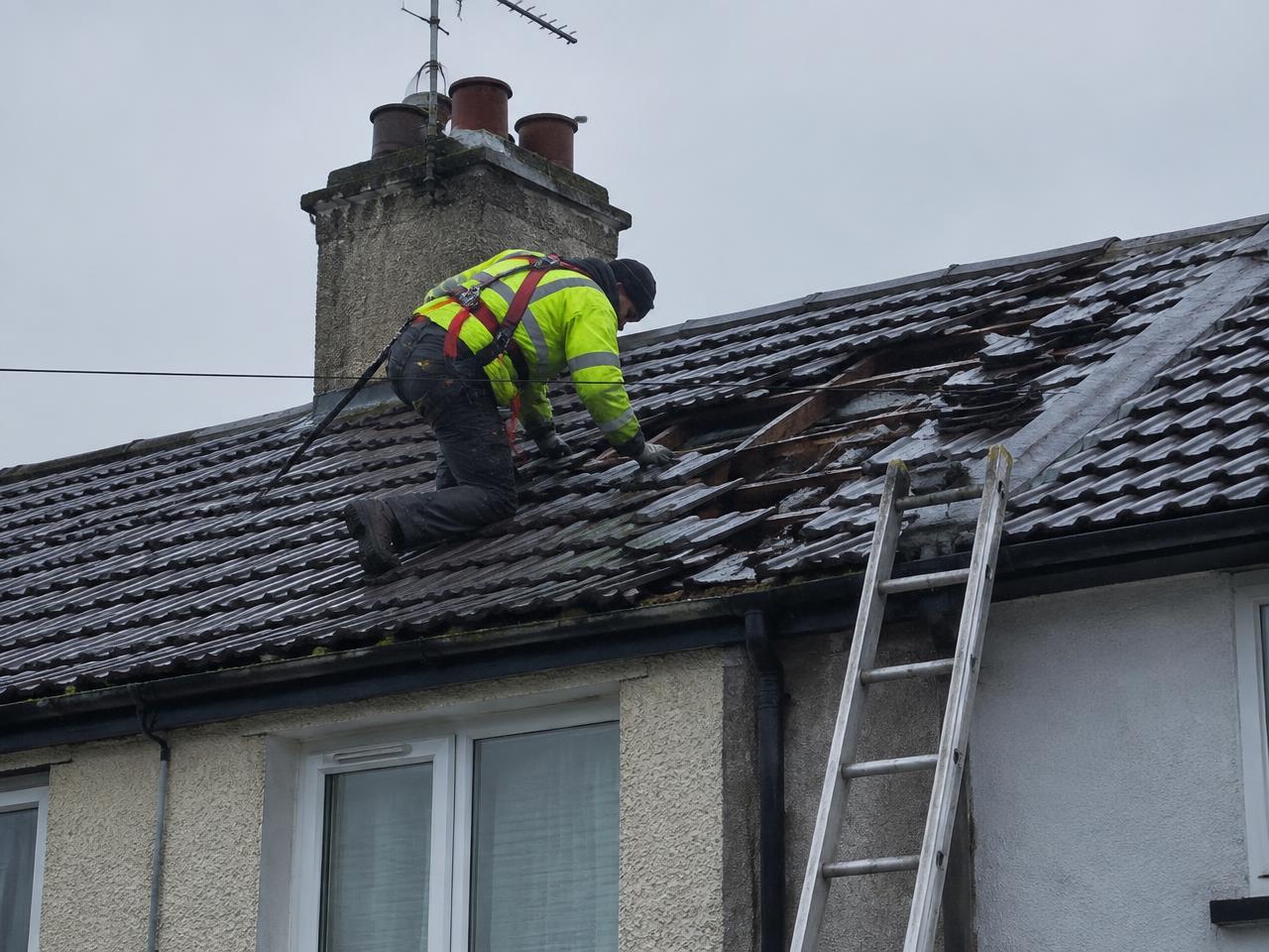 Roofer repairing storm-damaged tiles